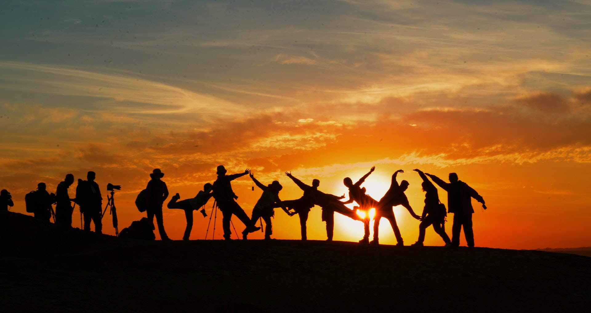 A group of people outside holding hands with a sunset in the background
